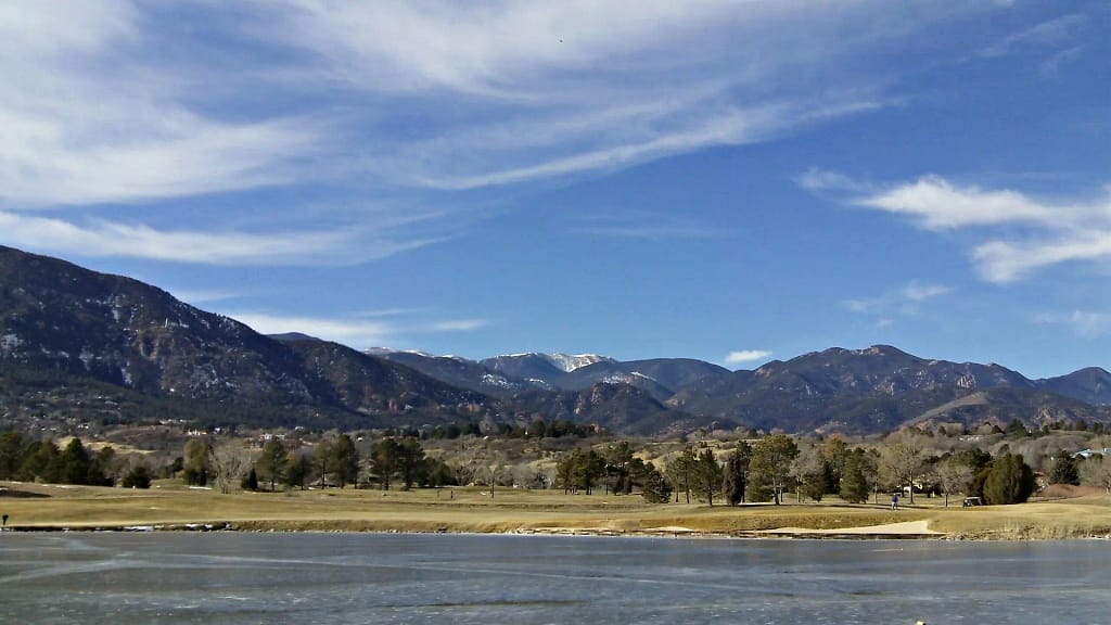 Mountain lake with grassy shore and blue sky
