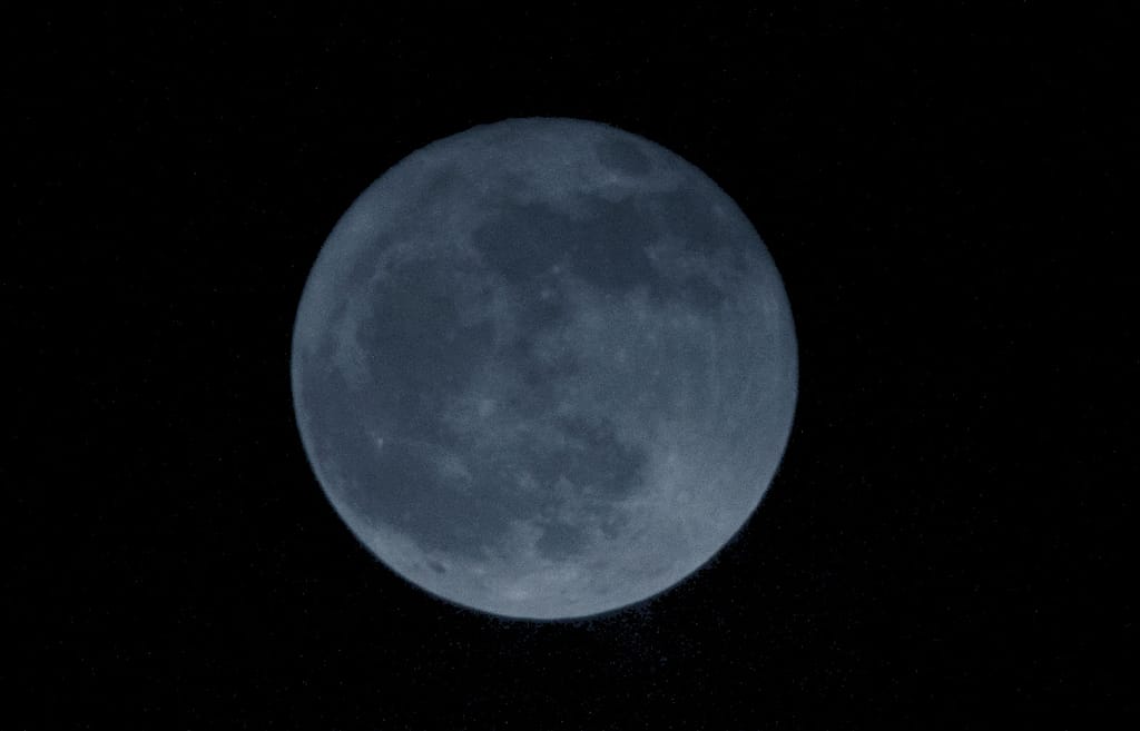 Blue-tinted full moon against black sky