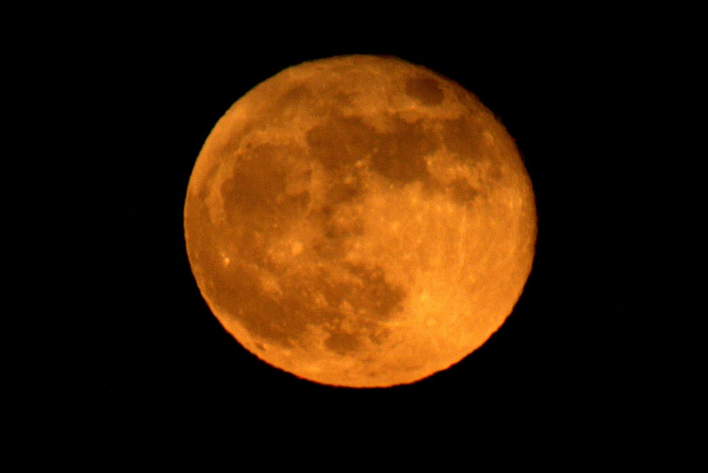 Orange full moon in dark night sky