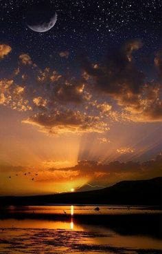 Crescent moon and stars over golden sunset lake