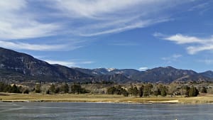 Mountain lake with grassy shore and blue sky