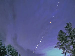 Lunar eclipse sequence over silhouetted trees