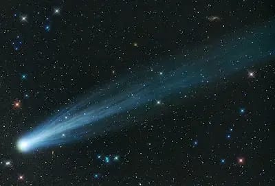 Bright comet with long icy tail across stars