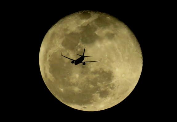 Plane silhouette against large full moon