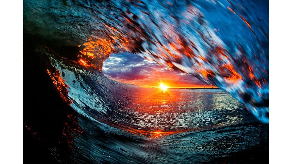 Sunset through curling ocean wave barrel